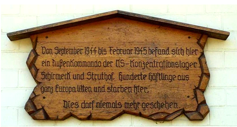 1970 von Häftlingen angebrachte Gedenktafel: Von September 1944 bis Februar 1945 befand sich hier ein Außenkommando der NS-Konzentrations-lager Schirmeck und Struthof. Hunderte Häftlinge aus ganz Europa litten und starben hier. Dies darf niemals mehr geschehen. Gedenktafel